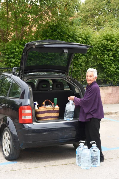 Mulher velha baixando a compra de carro — Fotografia de Stock