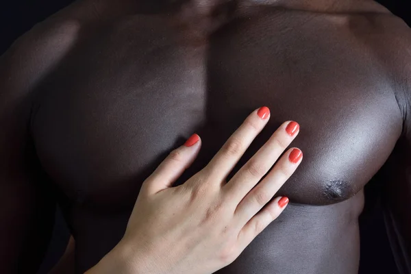 Beyaz bir kadının el siyah bir adamın kaslı bir göğsünde — Stok fotoğraf