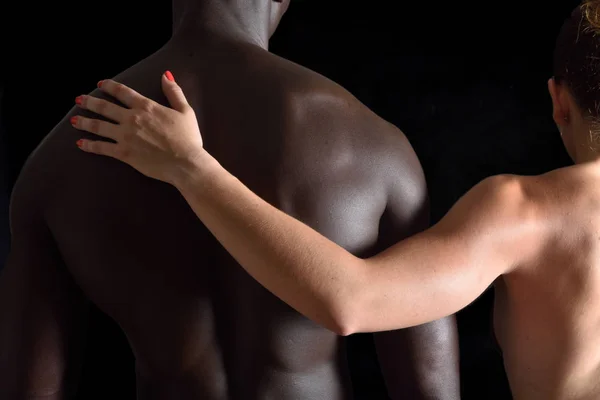 O abraço de um casal interracial no fundo preto — Fotografia de Stock