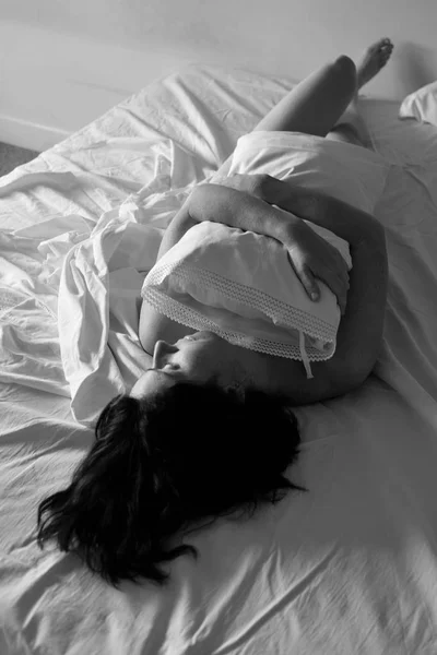 Woman lying in bed embracing a pillow — Stock Photo, Image