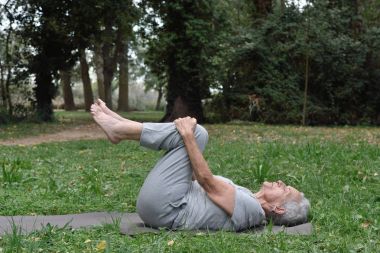 açık havada yoga yaparken yaşlı bir kadın