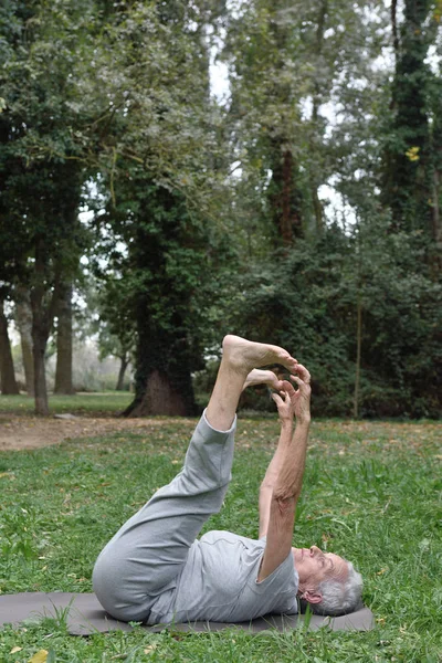 an older woman doing yoga outdoors