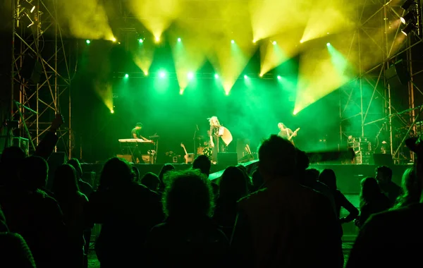 Gente siluetas delante de luces de escenario brillantes, música — Foto de Stock