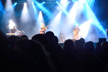 İnsanlar siluetleri önünde parlak sahne ışıkları,