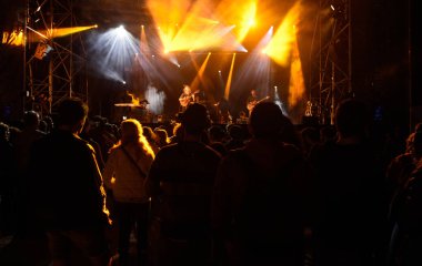 İnsanlar siluetleri önünde parlak sahne ışıkları, müzik