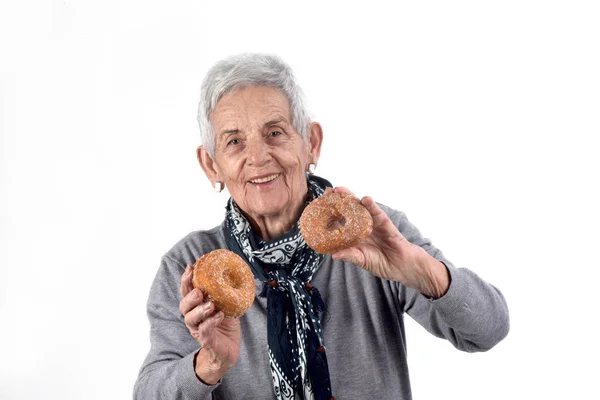 Senior Kvinna äta donut på vit — Stockfoto