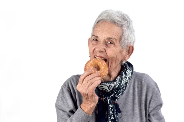 Senior woman eating donut on white — Stock Photo, Image