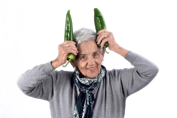 Старша жінка їсть перець на білому — стокове фото