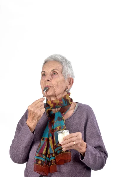 Старша жінка їсть йогурт на білому тлі — стокове фото