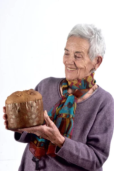 Yaşlı kadın panettone beyaz arka plan üzerinde yemek — Stok fotoğraf