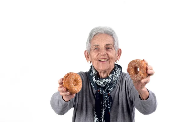 Senior woman eating donut on white — Stock Photo, Image