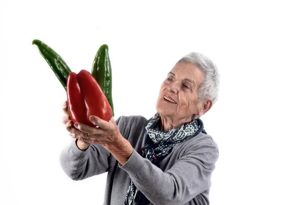 Senior kvinna äter peppar på vit — Stockfoto