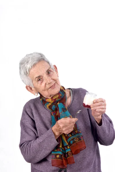 Senior woman eating yogurt on white background — Stock Photo, Image