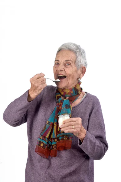 Mujer mayor comiendo yogur sobre fondo blanco —  Fotos de Stock