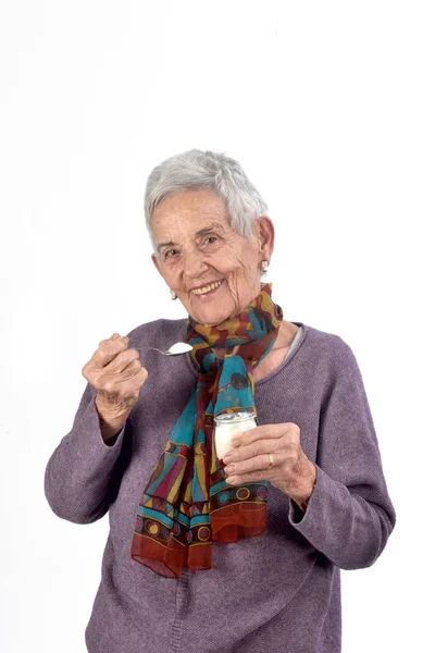 Senior vrouw yoghurt eten op witte achtergrond — Stockfoto