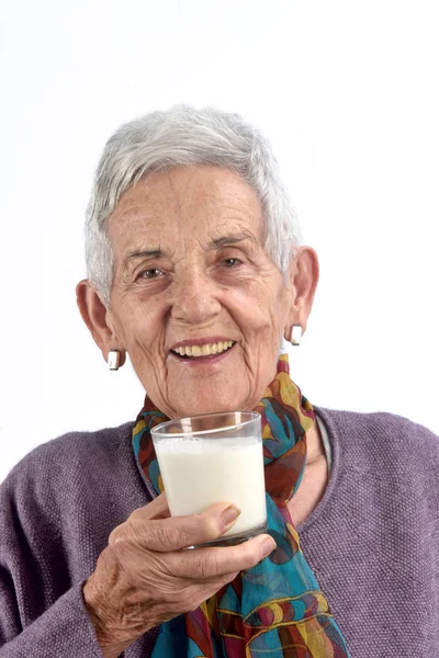 Senior Kvinna dricka mjölk på vit bakgrund — Stockfoto