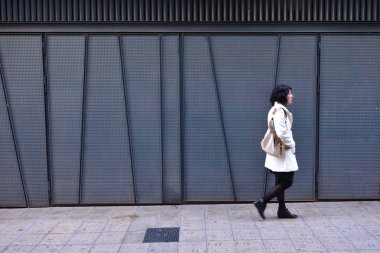 bir demir doku duvar yanında yürüyen kadın