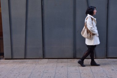 bir demir doku duvar yanında yürüyen kadın