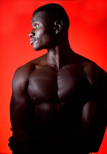 Retrato de un hombre africano sin camisa sobre fondo rojo — Foto de Stock