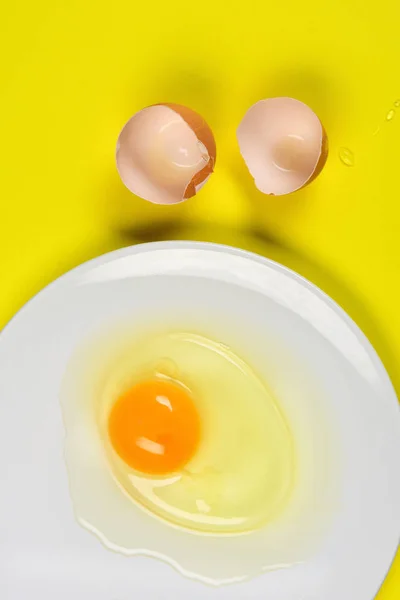Cracked egg on yellow background — Stock Photo, Image