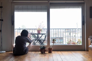 oturma ve pencereden dışarı bakarak üzgün kadın