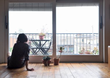 oturma ve pencereden dışarı bakarak üzgün kadın