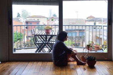 oturma ve pencereden dışarı bakarak üzgün kadın