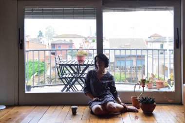 oturma ve pencereden dışarı bakarak üzgün kadın