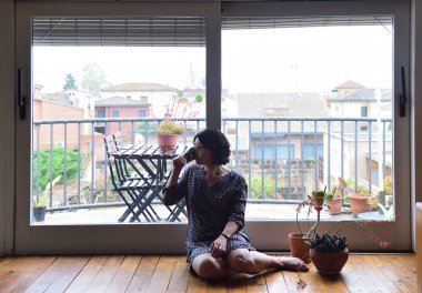 oturma ve pencereden dışarı bakarak üzgün kadın