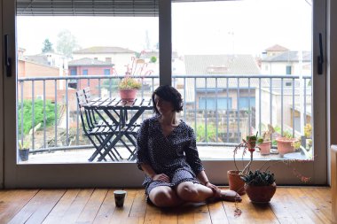 oturma ve pencereden dışarı bakarak üzgün kadın