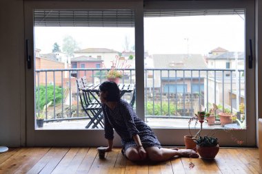 oturma ve pencereden dışarı bakarak üzgün kadın