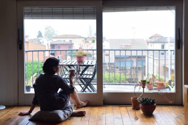 oturma ve pencereden dışarı bakarak üzgün kadın