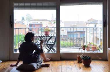 oturma ve pencereden dışarı bakarak üzgün kadın