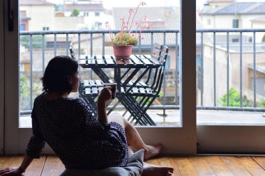 oturma ve pencereden dışarı bakarak üzgün kadın