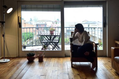 bir koltuk bir pencerenin önünde oturan kadın