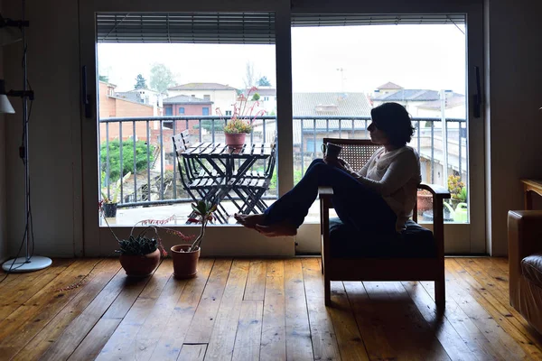 bir koltuk bir pencerenin önünde oturan kadın