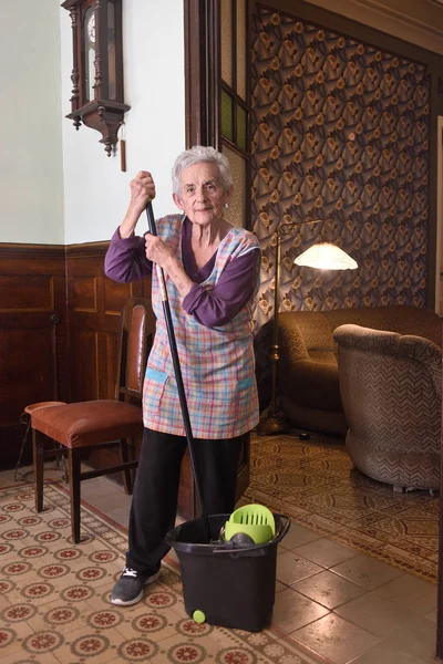 Mulher mais velha com esfregona fazendo o chão de sua casa — Fotografia de Stock