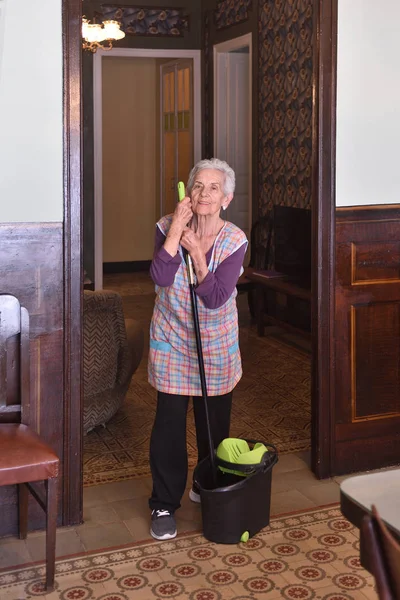 Femme plus âgée avec serpillière faisant le sol de sa maison — Photo