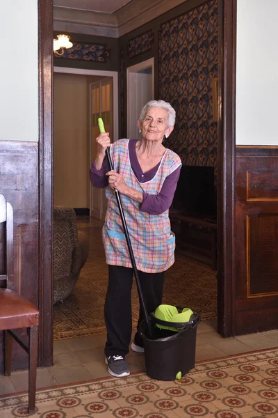 Mulher mais velha com esfregona fazendo o chão de sua casa — Fotografia de Stock