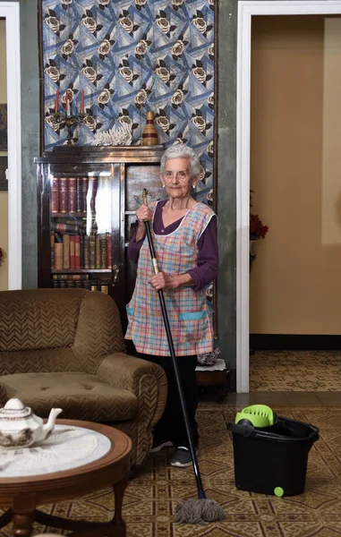 Onun evin katında yapım paspas ile yaşlı kadın — Stok fotoğraf