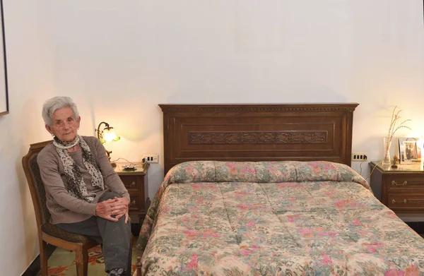 Portret van een bejaarde vrouw in een slaapkamer — Stockfoto