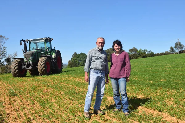 Ritratto di una coppia di agricoltori e trattore sul campo — Foto Stock