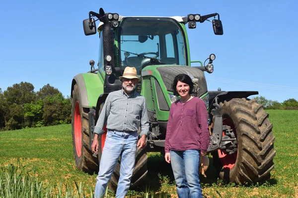 Retrato de um casal de agricultores e trator em campo — Fotografia de Stock