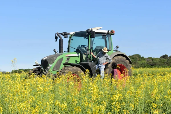 Paar van boeren in een canola-veld met een trekker — Stockfoto