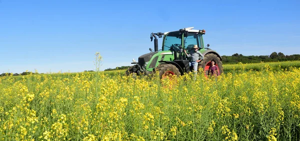 Paar van boeren in een canola-veld met een trekker — Stockfoto