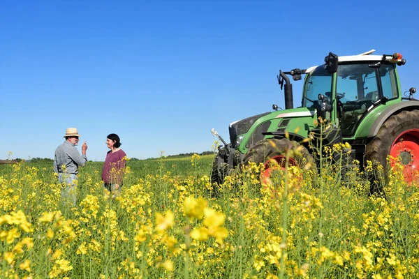 Paar van boeren in een canola-veld met een trekker — Stockfoto