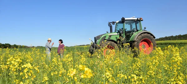 Paar van boeren in een canola-veld met een trekker — Stockfoto