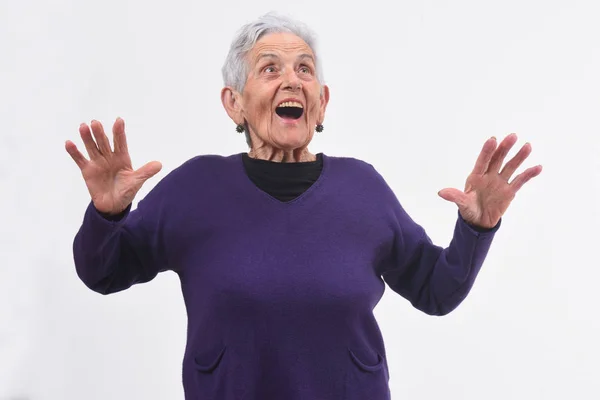 Äldre kvinna med en förvånad över ansikte och upphöjda händer på vita bac — Stockfoto