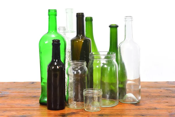 Группа бутылок и стеклянных банок на деревянном столе с белым баком — стоковое фото