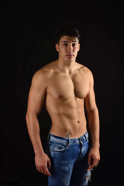 Portret van jonge man met romp naakt met jeans op zwarte rug — Stockfoto
